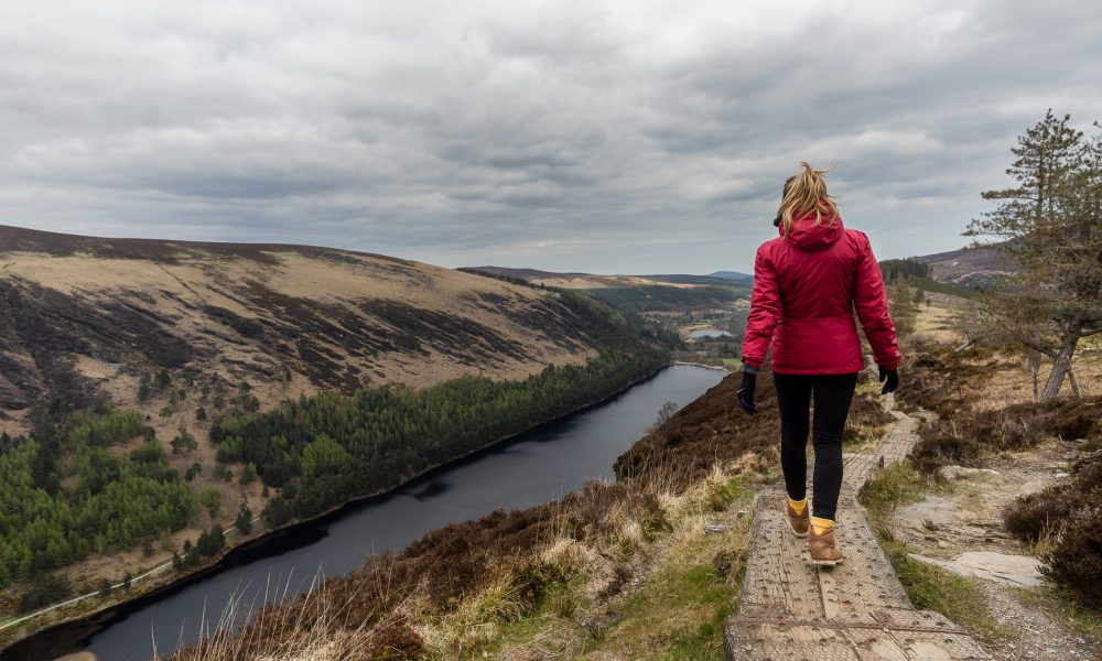 Woman walking along a path by a river in a scenic landscape