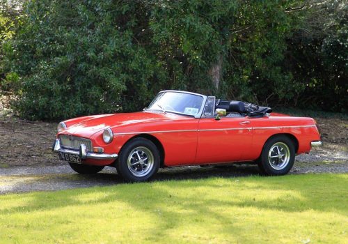 Red MGB Roadster parked on a grassy area