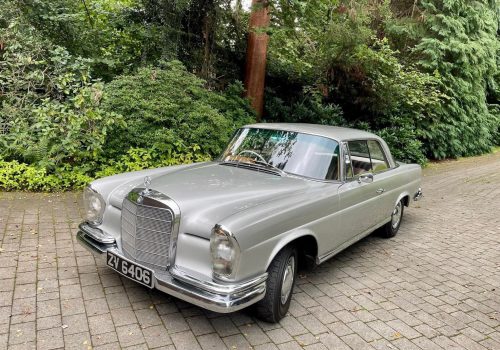 Silver Mercedes 220SEB Coupe parked on a stone pathway